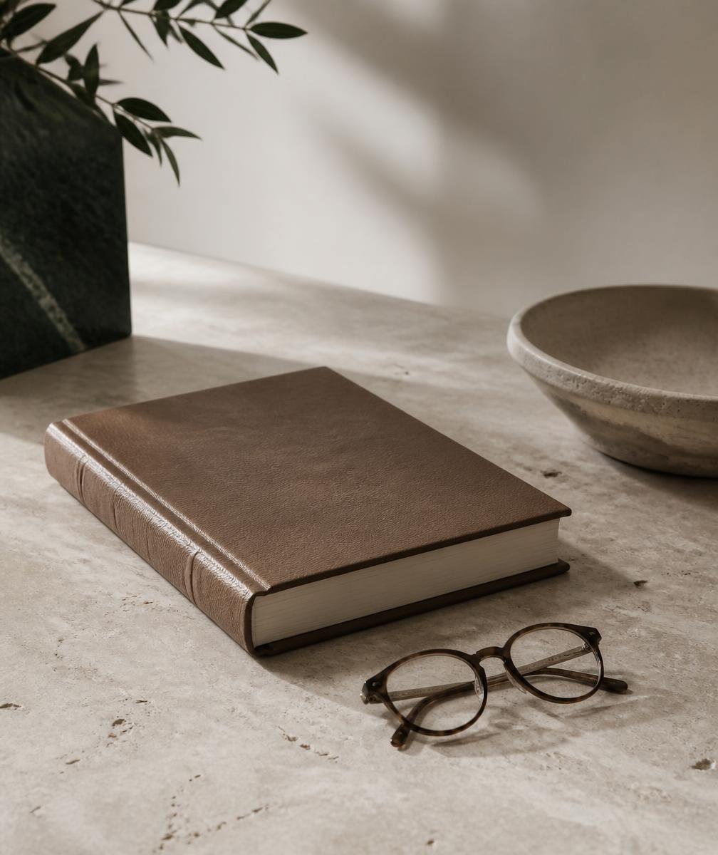 Mesa de trabalho sóbria com livro e óculos, em tons neutros